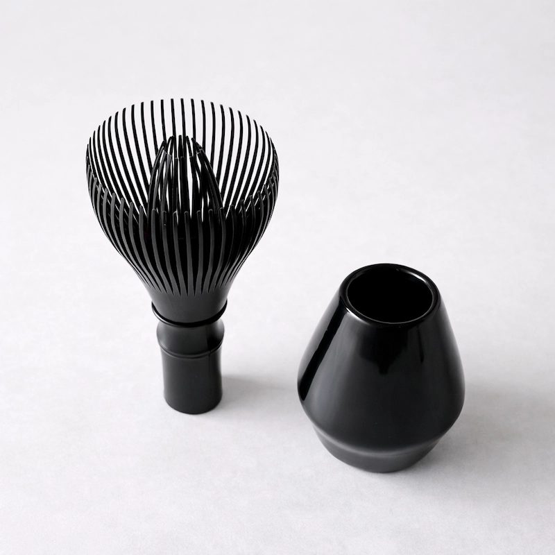 Black resin matcha whisk with matching holder, minimalist design, shown as a functional set for drying and maintaining the shape of the whisk.